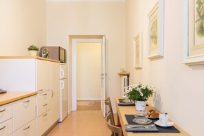 A narrow hallway with a kitchen on one side, a dining area with a table set for two, and a door leading to another room. - Palazzo Garibaldi - My Home In Como (Como)