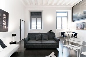 Ein modernes Wohnzimmer mit einer grauen Couch, einem weißen Sofa und einem Essbereich mit Stühlen und einem Tisch.