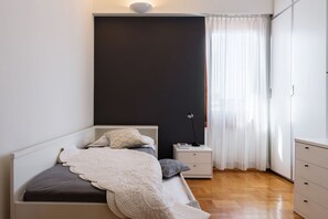 A bedroom with a bed, bedside table, lamp, and a wardrobe.