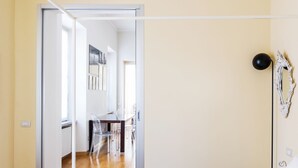 A hallway with a dining area, a black floor lamp, and a white abstract art piece on the wall. - Via Rusconi 10 - My Home In Como (Como)