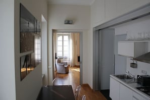 Ett modernt kök med en matplats, utsikt över vardagsrummet och en hall som leder till en dörr.