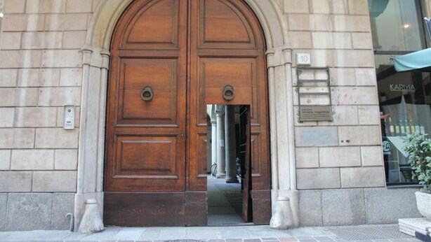 A large wooden double door with a stone archway, a small plaque, and a number '10' sign on the wall. - Via Rusconi 10 - My Home In Como (Como)