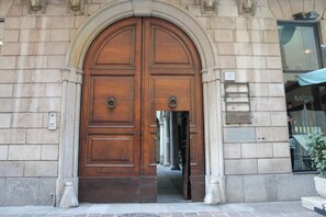 A large wooden double door with a stone archway, a small plaque, and a number '10' sign on the wall.