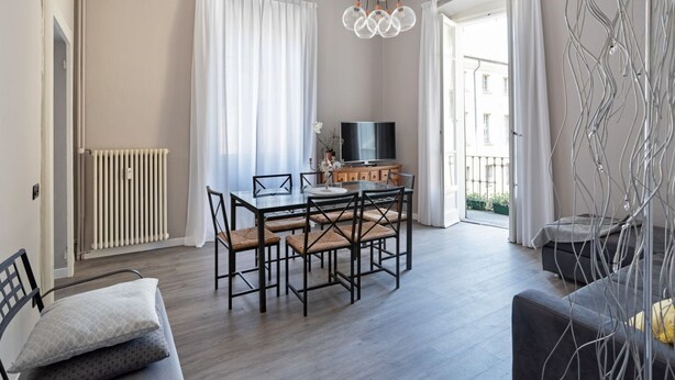 Ett modernt vardagsrum med ett matbord, stolar, en soffa, en tv och ett element.