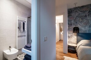 A modern bathroom with a bidet, towel rack, and a patterned wall.
