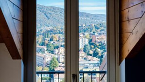 A view through a window with wooden framing, revealing a town with buildings and hills in the background.