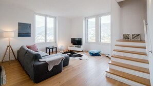 A modern living room with a sofa, TV, and a staircase.