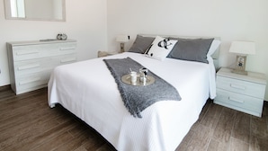 Une chambre bien rangée, avec un lit, des tables de chevet, une commode et un miroir.