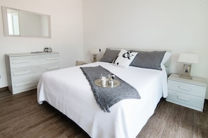 A neatly arranged bedroom with a bed, bedside tables, a dresser, and a mirror.