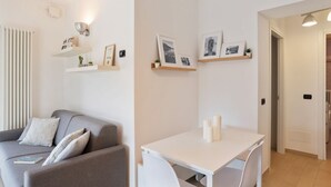 Una sala de estar moderna con un sofá gris, una mesa blanca y estantes con fotografías.