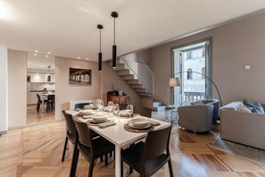 Um espaço de estar moderno com área de jantar, escada e vista para o exterior.