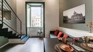 A modern interior with a staircase, a dining area with a table set for two, and a framed picture on the wall. - 06 Funicolare Visconti - My Home In Como (Como)