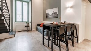 A modern dining area with a table, chairs, and a wall-mounted light fixture. - 06 Funicolare Visconti - My Home In Como (Como)