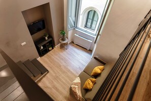 Moderni olohuone, jossa on sohva, televisio, huonekasvi ja ikkuna, josta on näkymä.