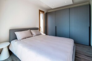Ein modernes Schlafzimmer mit einem Bett, einem kleinen runden Tisch und einem Kleiderschrank.
