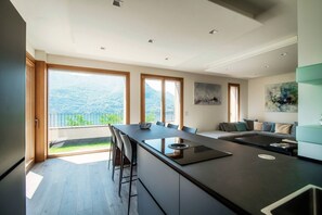 A modern kitchen with a large island, a dining area, and a sofa.