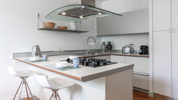 A modern kitchen with a central island, bar stools, a stainless steel kettle, and a coffee machine. - MG Home - MyHomeInComo (Como)