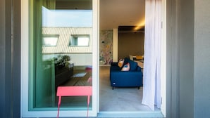 Un intérieur moderne avec une porte-fenêtre coulissante donnant sur un espace de vie agrémenté d’un canapé bleu et d’une petite table.