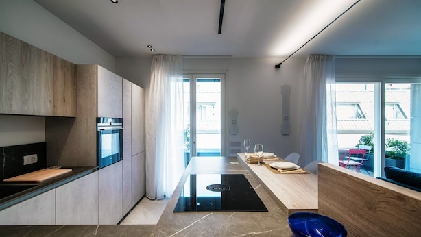 Une cuisine moderne dotée d’un îlot central, d’appareils électroménagers intégrés et d’un coin repas offrant une vue agréable.