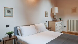 A bedroom with a bed, bedside table, lamp, dresser, and radiator. - The Artist's Nest - My Home In Como (Como)