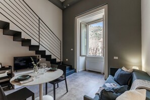 Un salon moderne avec un escalier, un coin repas et une grande fenêtre offrant une belle vue.