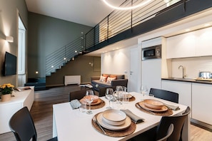 A modern kitchen with a microwave, a dining area with a table set for four, and a staircase leading to an upper level.
