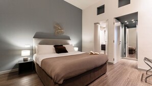 Camera da letto moderna con un letto grande, comodini, una ventola a muro e una porta che dà su un'altra stanza.