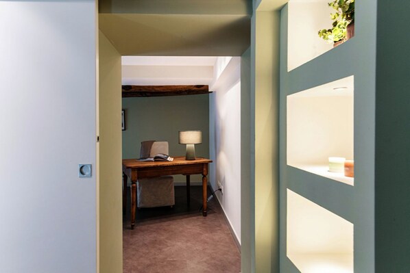 A hallway with a desk, chair, lamp, and a plant. - 02 Duomo Visconti - My Home In Como (Como)