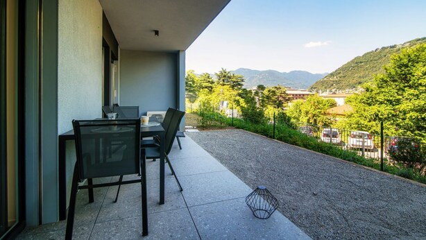 Une terrasse avec une table et des chaises, une petite lampe décorative et une vue sur un paysage vallonné.