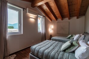 Un dormitorio con dos camas, ventanas amplias, vigas de madera en el techo y vistas al exterior.