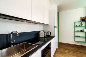 A modern kitchen with a stainless steel sink, a black countertop, and white cabinets.