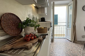 Una cocina con tabla de madera, cesta tejida y planta en maceta.