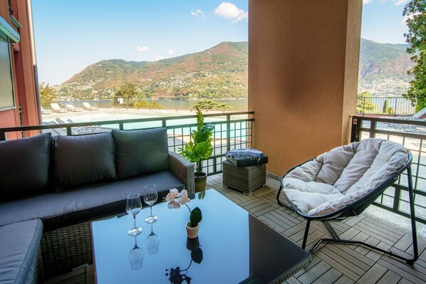 A balcony with a sofa, a chair, a table with glasses, and a potted plant. - Florissa - My Home In Como (Blevio)