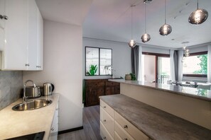 A modern kitchen with a sink, cabinets, and pendant lights. - Florissa - My Home In Como (Blevio)