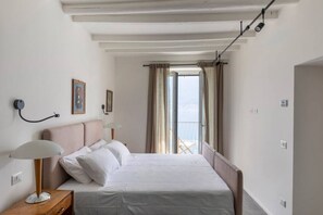A bedroom with a bed, bedside lamps, a picture on the wall, and a balcony with curtains. - La Casa del Pescatore - MyHomeInComo (Colonno)