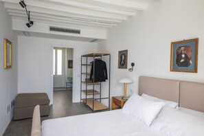 Un dormitorio con cama, mesita de noche, lámpara, armario y un cuadro en la pared.