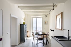 Una cocina moderna con un lavamanos, armarios y una zona de comedor con sillas y una mesa.