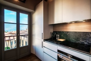 A modern kitchen with a large window, a stove, and a view of the cityscape.