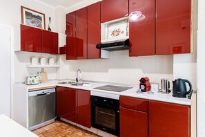 A modern kitchen with red cabinets, a dishwasher, an oven, a sink, and a coffee maker. - Cernobbio Garden View - My Home in Como (Cernobbio)