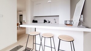 A modern kitchen with white cabinetry, a white countertop, and three stools. - Bella Lì - MyHomeInComo (Menaggio)