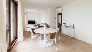 A modern dining area with a round table, chairs, and a TV in the background. - Bella Lì - MyHomeInComo (Menaggio)