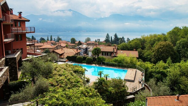 A residential area with a swimming pool, houses with red-tiled roofs, and a mountain backdrop. - Bella Lì - MyHomeInComo (Menaggio)