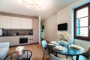 Een moderne keuken met een eethoek, een tv aan de muur en een raam met luiken.