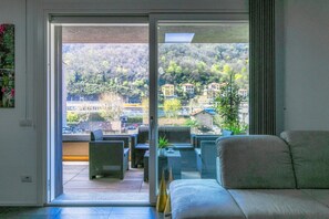 Habitación con puerta de vidrio corrediza que da a un patio al aire libre con muebles de mimbre y vistas a una colina con edificios.