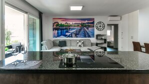 Eine moderne Küche mit einer großen Kochinsel, einem Essbereich mit einer Couch und einem Stadtbild an der Wand.