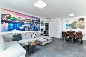 A modern living room with a sofa, coffee table, and dining area with chairs.