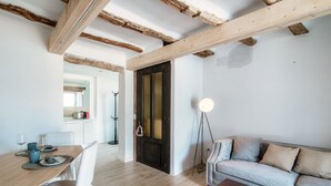 A modern living room with a wooden dining table, white chairs, a sofa, and a floor lamp. - Acqua - My Home in Como (Moltrasio)