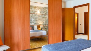 A bedroom with a bed, a nightstand, a mirror, and a wardrobe.