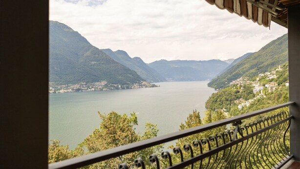 A balcony with a view of a lake surrounded by mountains.