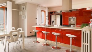 A modern kitchen with a red island, stainless steel appliances, and bar stools.